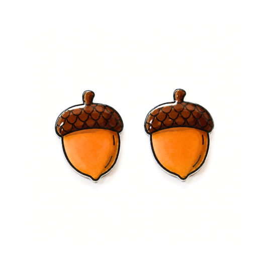 A pair of acorn-shaped stud earrings with glossy orange bodies and brown scaly caps outlined in black, displayed on a clean white background.
