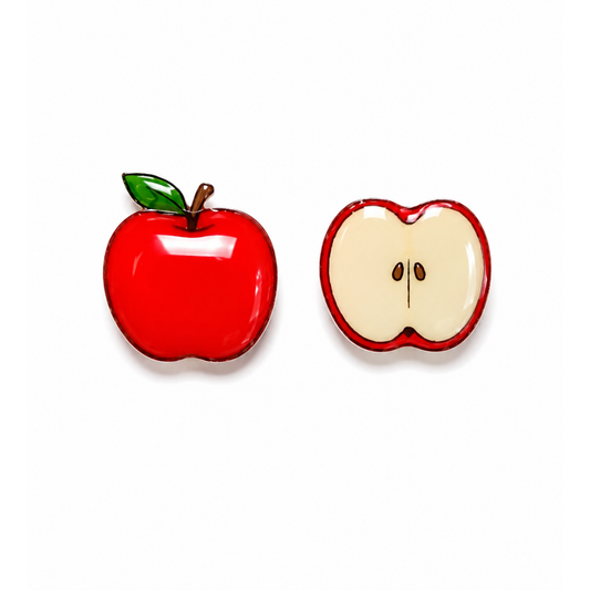 Two apple-shaped titanium stud earrings on a white background, one whole red apple with a green leaf and brown stem, and one cross-section of a red apple showing cream-colored flesh.